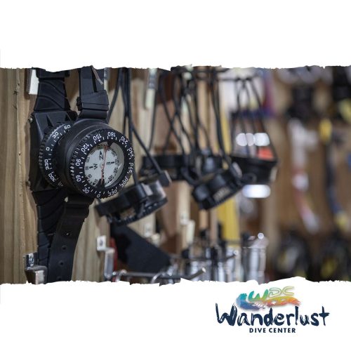 Multiple dive computers and analog gauges hanging in the Wanderlust Dive Center gear room