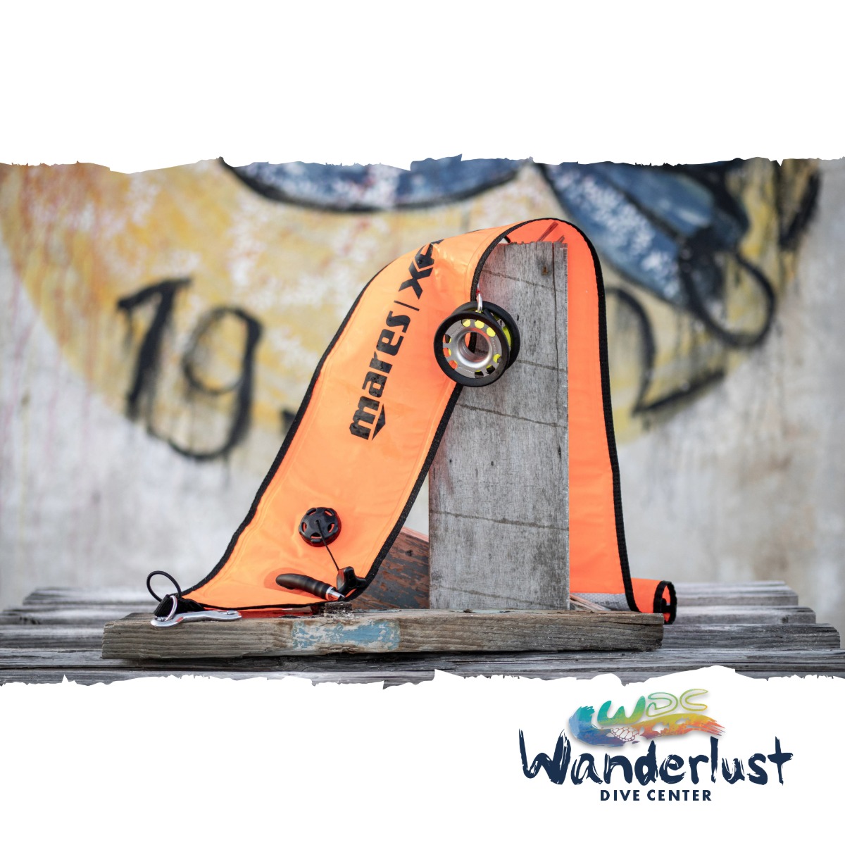 Orange dive cutting tool placed on driftwood near a Bonaire shore entry